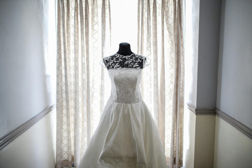 A beautiful bridal gown displayed on a mannequin, illuminated by natural light from a window. Affordable Wedding Ideas in Nairobi)