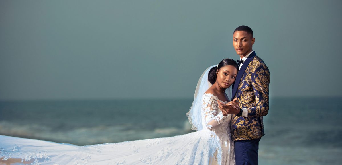 A couple embraces on a beach in Togo, showcasing elegant wedding attire.