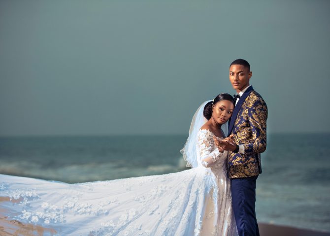 A couple embraces on a beach in Togo, showcasing elegant wedding attire.