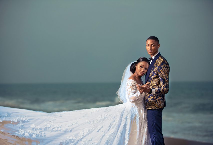 A couple embraces on a beach in Togo, showcasing elegant wedding attire.