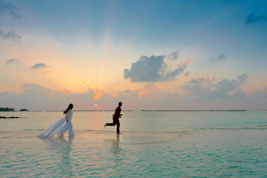 A couple enjoys a romantic moment running on a tropical beach during sunrise, capturing love and joy. Simple wedding in Kenya